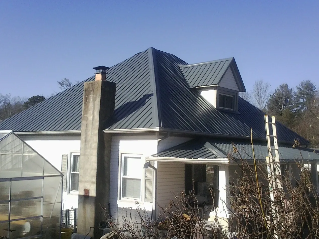 Dark blue standing seam metal roof on a white farmhouse with dormer — Slate & Tile Roof Repair by Roofing Brothers in Pegram