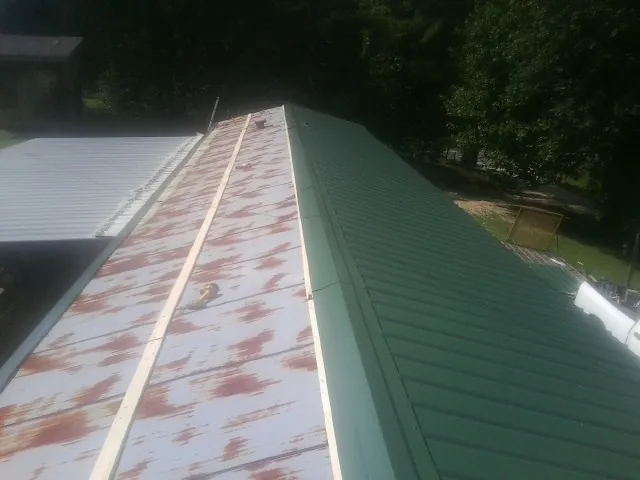 Old rusted panels beside newly installed green metal roofing — Wind Damage Roof Repair by Roofing Brothers in Pegram
