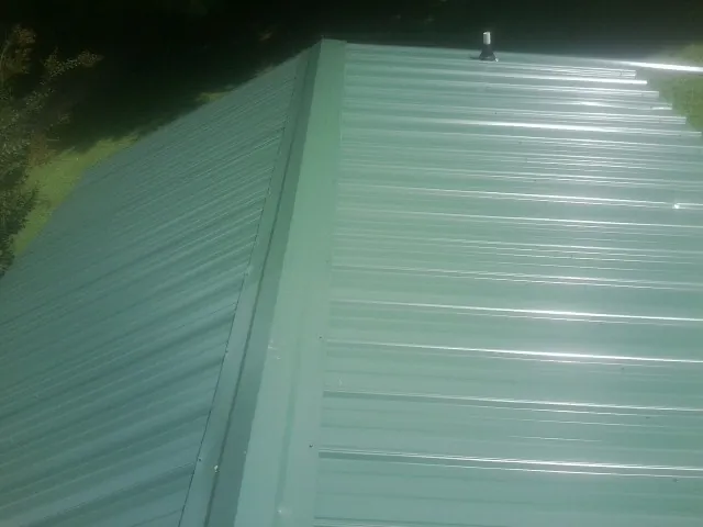 New green metal panels meeting at the ridge of a roof — Flat Roof Repair work by our crew in Pegram