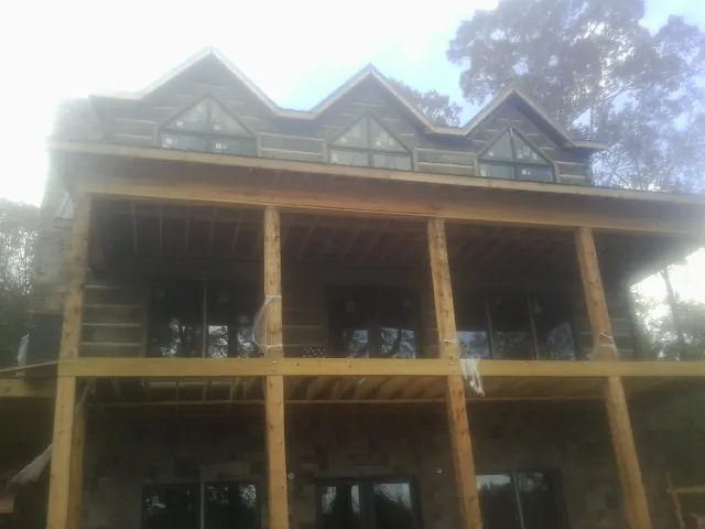 Dormers and porch framing on a large log home under construction — Roof Coating work by our crew in Pegram