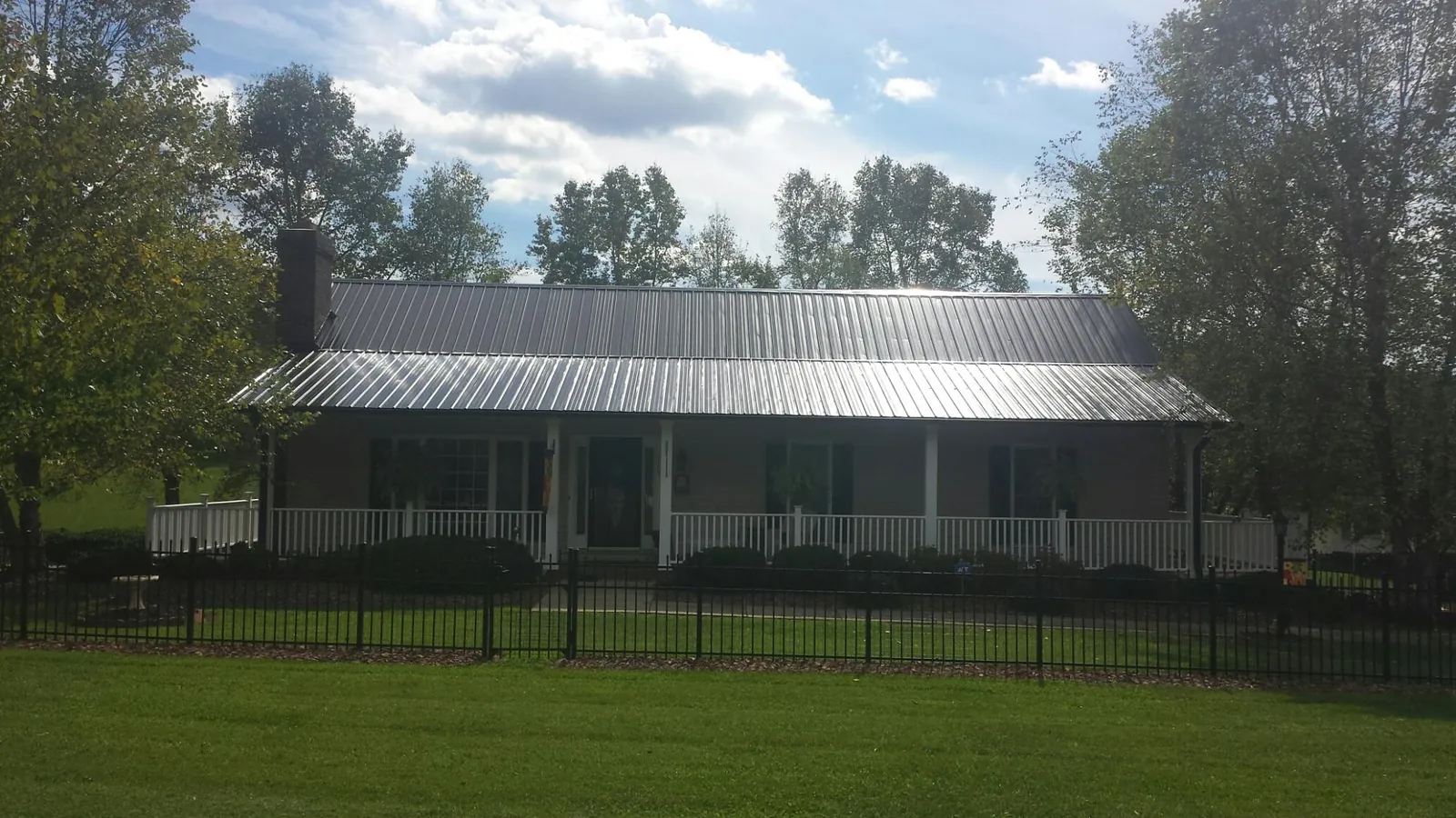 Gray metal roof on a brick ranch with a full width front porch — Gutter Guard Installation work by our crew in Pegram